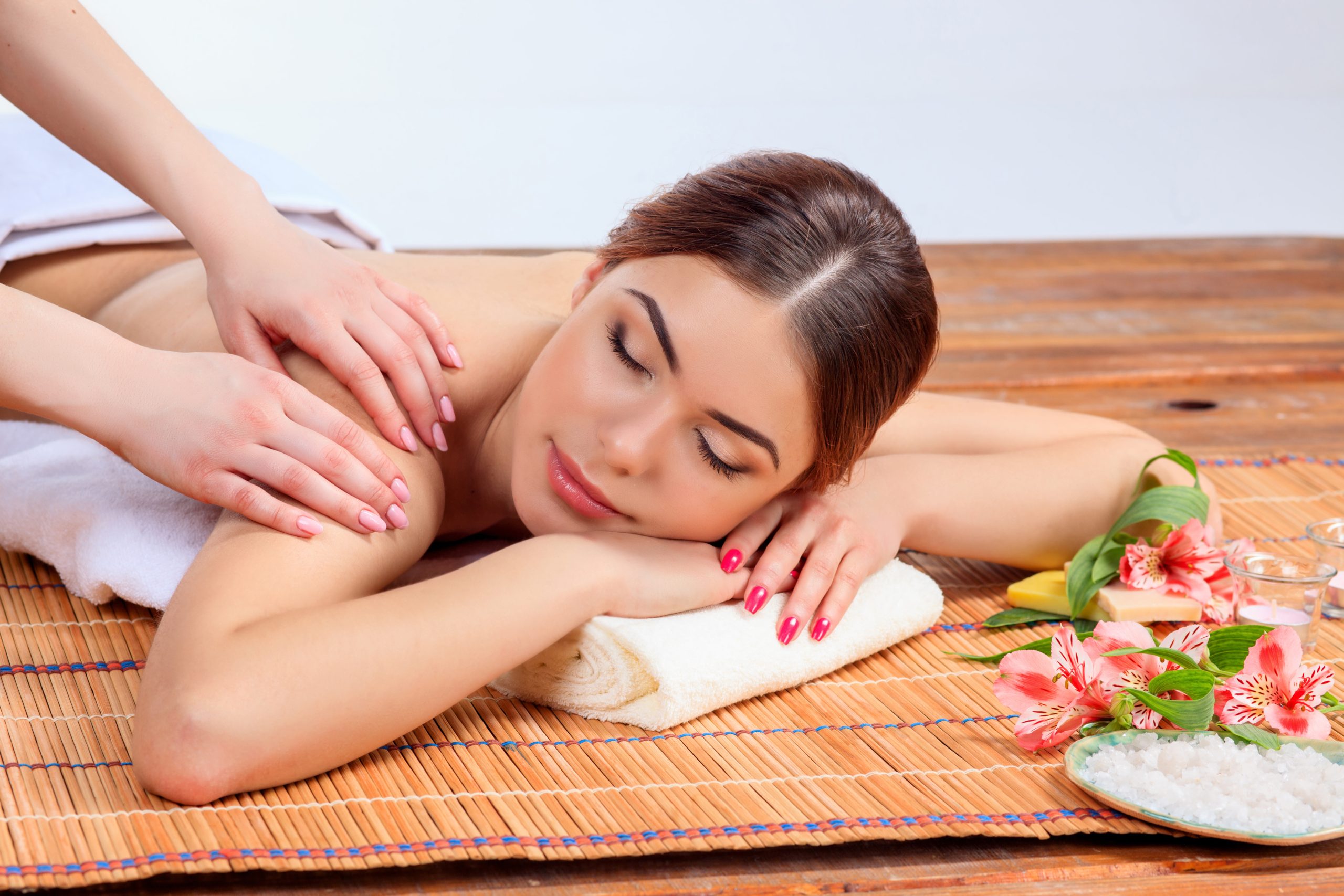 Beautiful young woman at a spa salon resting on a straw mat. Concept of body care and relaxation