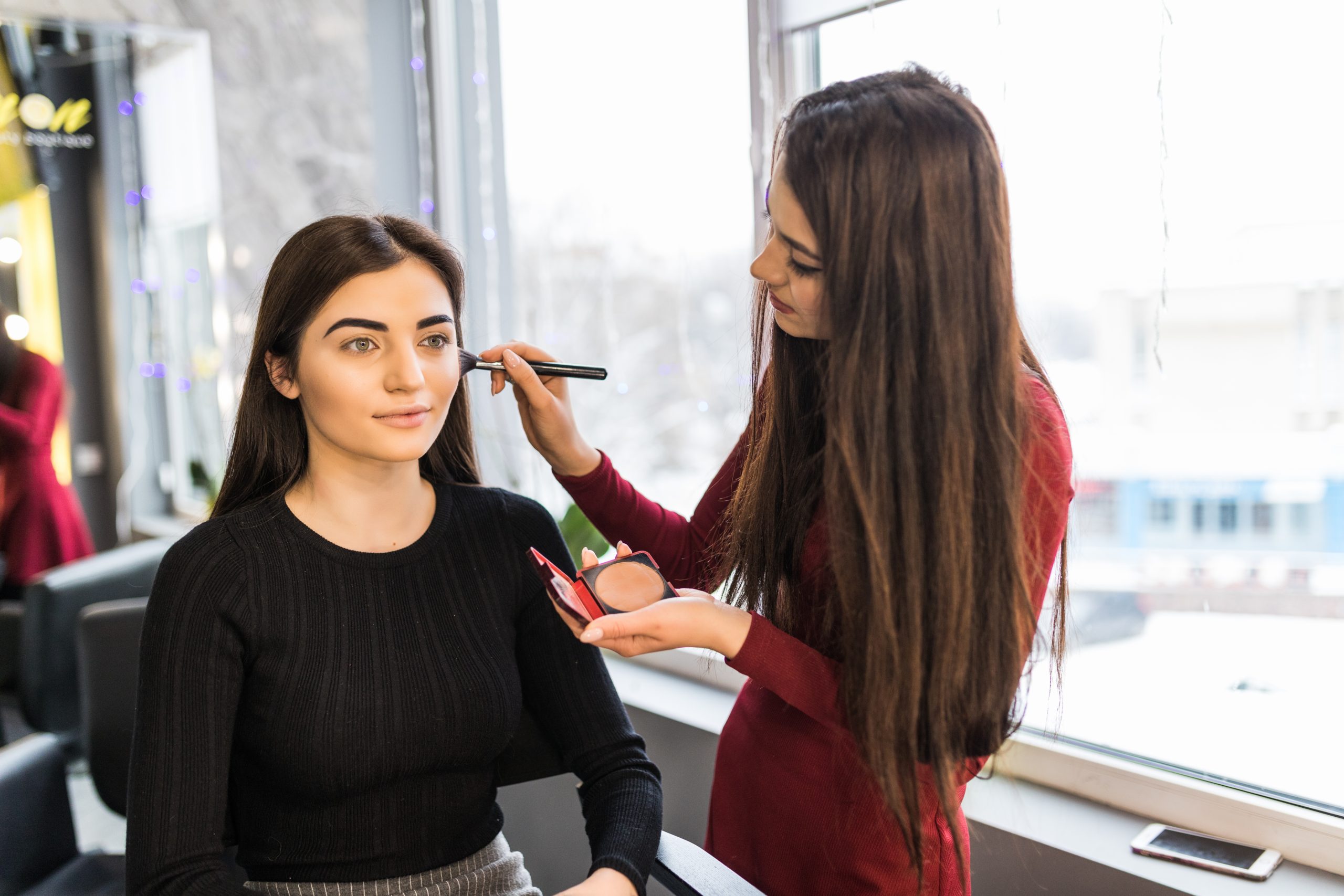 Young model with green eyes is having make-up procedure